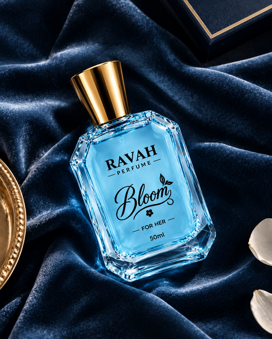 A 50ml bottle of RAVAH PERFUME 'Bloom' fragrance, featuring a light blue faceted glass bottle and a metallic gold cap, set against a luxurious dark blue velvet background with decorative gold and white elements.
